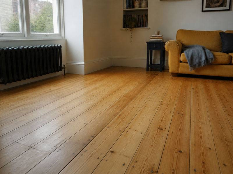 Sanded and oiled original pine floorboards in a furnished tenement living room, gaps filled and finished with a warm matte oil