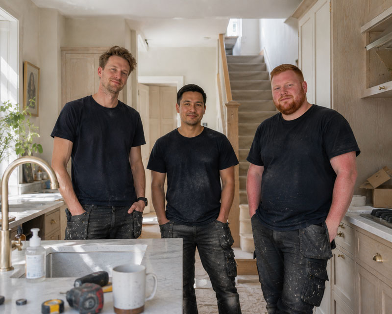 Liam and the L.S. Joinery team standing in a finished kitchen, tools and mugs on the countertop behind them