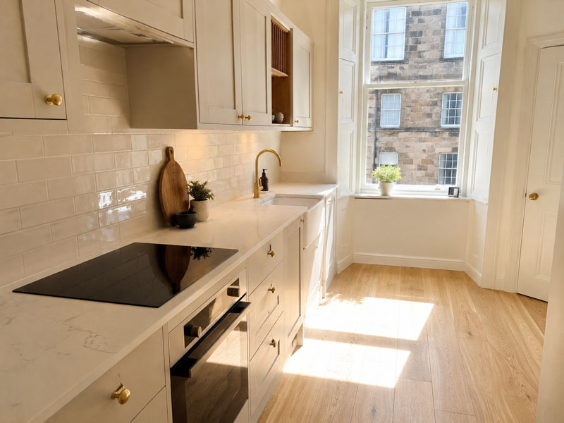 Finished shaker kitchen with marble-effect worktop, brass hardware and tiled splashback