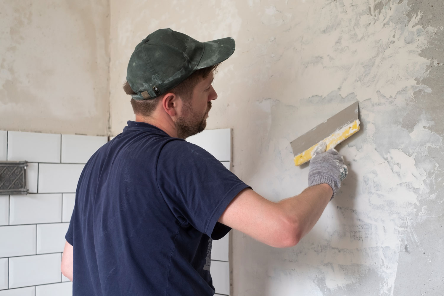 Plasterer patching and skimming a cracked wall beside bathroom tiling — Leith, Edinburgh