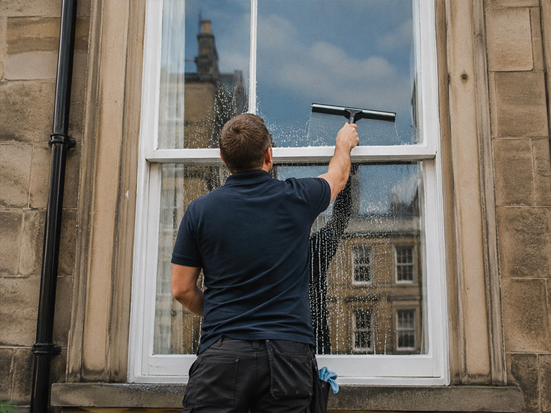 John cleaning a sash and case window in Edinburgh with a squeegee