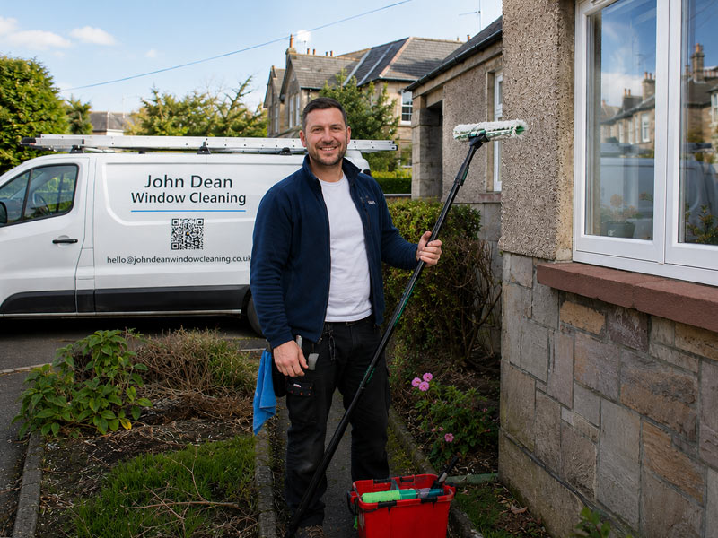 John Dean smiling beside his branded window cleaning van on a regular round in Edinburgh